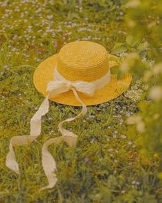 a yellow hat sitting on top of a lush green field next to wildflowers