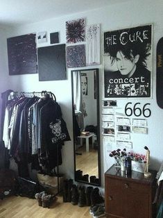 a room filled with lots of clothes and posters on the wall next to a mirror