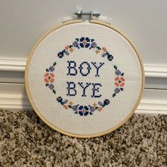 a close up of a cross stitch on a hoop with the words boy bye in it