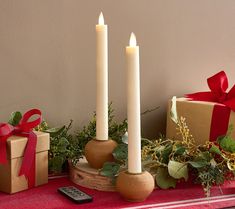 three candles sitting on top of a table next to presents and a cell phone with a red ribbon