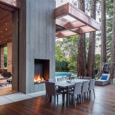 an outdoor dining area with a fire place in the center and wood flooring on the outside