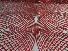 an artistic red sculpture made out of metal mesh