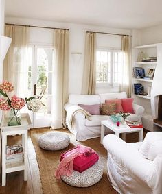 a living room filled with white furniture and lots of window sill space next to a fire place