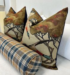 two pillows sitting on top of a couch next to a pillow with an image of a bird