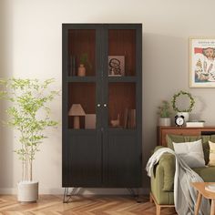 a living room filled with furniture and a tall wooden cabinet next to a green couch