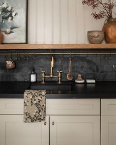 a kitchen with black counter tops and gold faucets on the wall above it