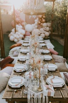 a long table set with white plates and pink napkins for a party or wedding