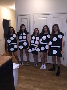 four girls are dressed up in black and white polka dot dresses, one is wearing a dress