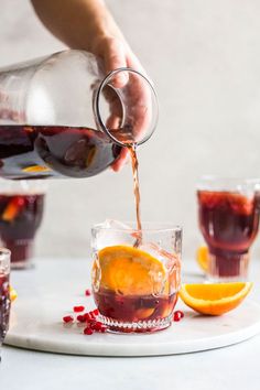 someone pours red wine into glasses with orange slices