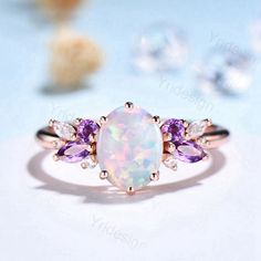 an opal and amethorate ring on a white surface with other jewelry items