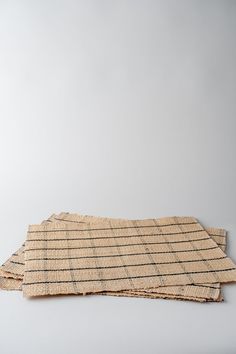 two pieces of woven material sitting on top of each other in front of a white wall