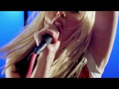 a woman with long blonde hair singing into a microphone