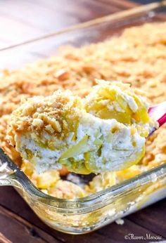 a scoop of ice cream is being lifted from a casserole dish with crumbs