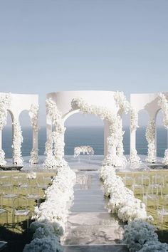 an outdoor wedding setup with white flowers and chairs