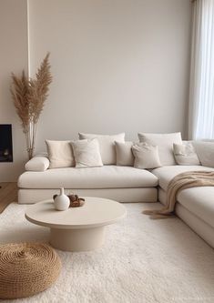 a living room filled with white furniture next to a fire place and a large window