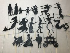 a group of black silhouettes on sticks in the shape of people and animals,