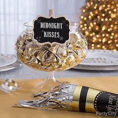 a table topped with a glass bowl filled with candy and a sign that says midnight kisses