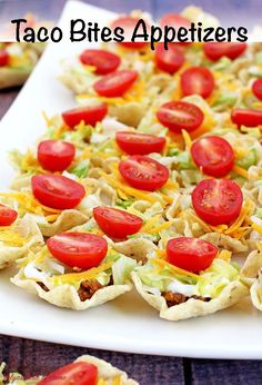 some taco shells with tomatoes and lettuce are on a white platter