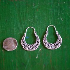 This is a larger size, sandcast arracada Mexican earring. It is the traditional arracada or crescent shape, so common on the earlobes of Mexican women, with a small flowers and leaves. They are 92.5% silver or sterling silver. It has a slight patina from oxidation to make them appear old. Handmade near Mexico City. Each earring is slightly different from the photo--they are handmade so there is a little variation in how close the flowers are to the edges. Arracada earrings naturally sit slightly Fiesta Party Decorations, Mexican Earrings, Mexican Women, Crescent Shape, Mexican Folk Art, Look In The Mirror, Sacred Heart, Flowers And Leaves, Small Flowers