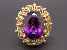 Jewelry Type: Ring Metal: 18k Yellow Gold Markings: 18k Measurements: 27mm x 24mm wide ( front face of ring) 3mm wide back of shank (most narrow area of band) 17mm high ( finger to top of ring) Weight: 15.1 grams Main Stone: Oval Cut Amethyst Gem Measurements: 17.7mm x 13mm x 11.7mm Gem Weight: 14ct total approx US Finger Size: 6 Video posted on our Instagram page @ CileoneJewelry #10358 Victorian Amethyst Ring In Yellow Gold, Gold Amethyst Oval Cabochon Ring, Oval Amethyst Ring With Large Stone, Fine Jewelry, Luxury Yellow Gold Amethyst Ring Oval Cabochon, Luxury Formal Amethyst Ring, Oval Cabochon, Rosé Angel, 1970s Jewelry, Flower Band, Coral Flowers