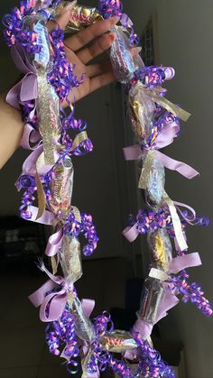 someone is holding up some candy wrapped in purple and gold ribbon with ribbons around it