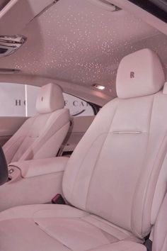 the interior of a luxury car with white leather seats and sparkling lights on the ceiling