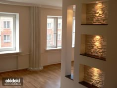 an empty living room with wood floors and stone fireplaces on the wall, in front of two windows