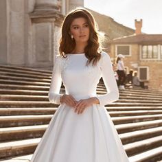 a woman in a white wedding dress standing on steps with her hand on her hip