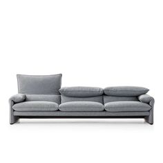 a gray couch with two pillows on the back and one pillow on the side, in front of a white background