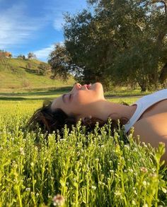 a woman laying in the grass with her eyes closed