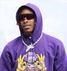 a man wearing a purple hoodie with a chain around his neck and sunglasses on