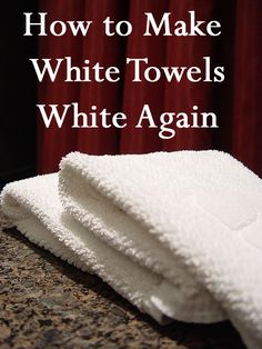 three white towels stacked on top of each other in front of a red curtained window