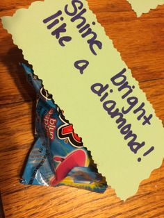 a candy bar wrapper sitting on top of a wooden table next to a piece of paper