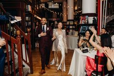 a bride and groom walk down the aisle at their wedding reception with guests clapping in the background