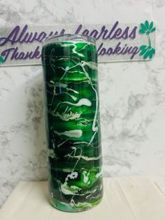 a green and white vase sitting on top of a marble counter next to a sign