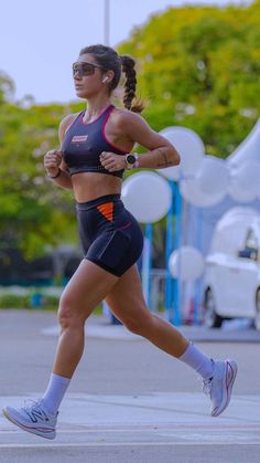 a woman running down the street in her sports bra top and shorts with sunglasses on