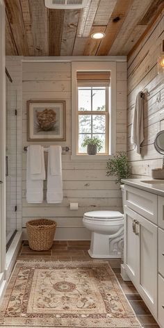 a white bathroom with wood paneling and a rug on the floor next to the toilet