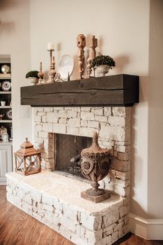 a stone fireplace in a living room with wood flooring and white brick mantles