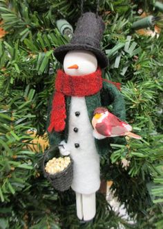 a snowman ornament hanging from a christmas tree with a bird on it