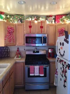 a kitchen decorated for christmas with snowman decorations on the wall and lights above the stove