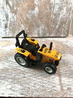 a yellow toy tractor sitting on top of a wooden table