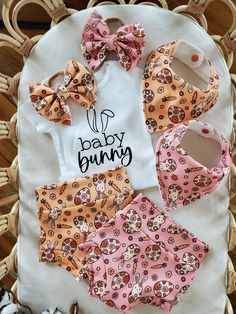 a baby bunny outfit and bib laying on top of a wicker basket next to shoes