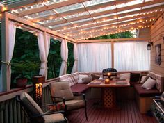 a covered deck with furniture and string lights on the ceiling is featured in this image