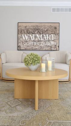 a coffee table with candles on it in front of a couch and wall hangings