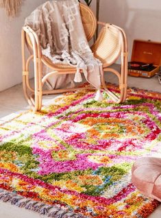 a colorful rug in the corner of a room with a chair and potted plant