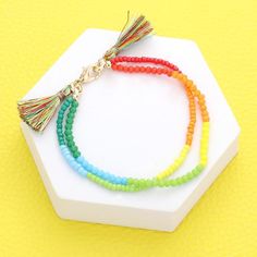 multicolored beaded bracelet with tassels on white hexagonal stand