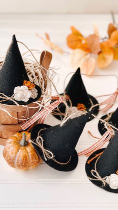 small black witches hats sitting on top of a table next to pumpkins and flowers