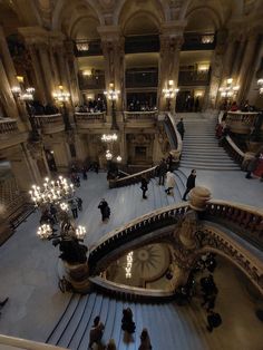 people are walking up and down the escalator in a building with chandeliers