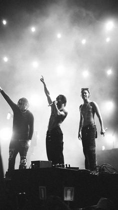 three men standing on top of a stage with their arms in the air