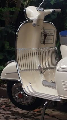 a white scooter parked next to a tree